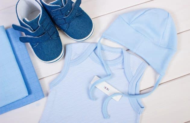 Pregnancy test with positive result and clothing for newborn, expecting for baby concept