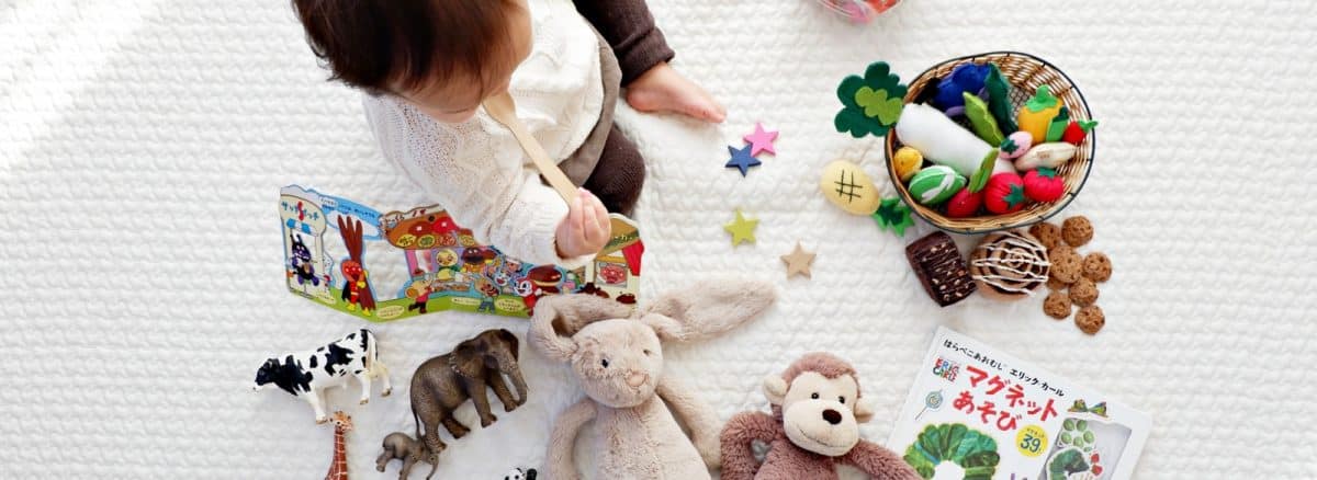 boy sitting on white cloth surrounded by toys