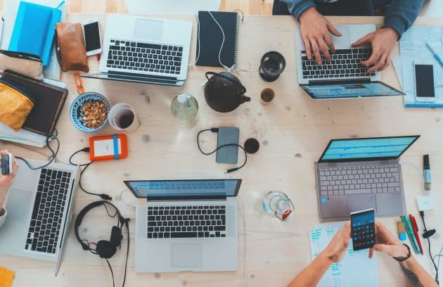 people sitting down near table with assorted laptop computers