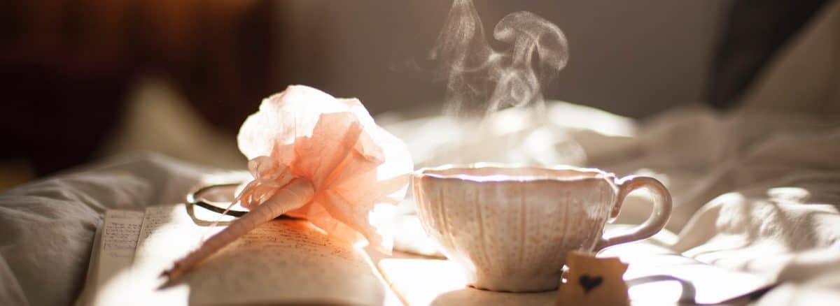 teacup on book beside pink flower decor