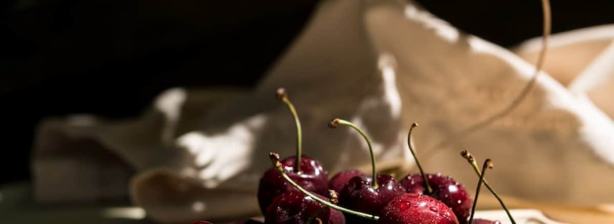 a glass bowl filled with cherries on top of a table