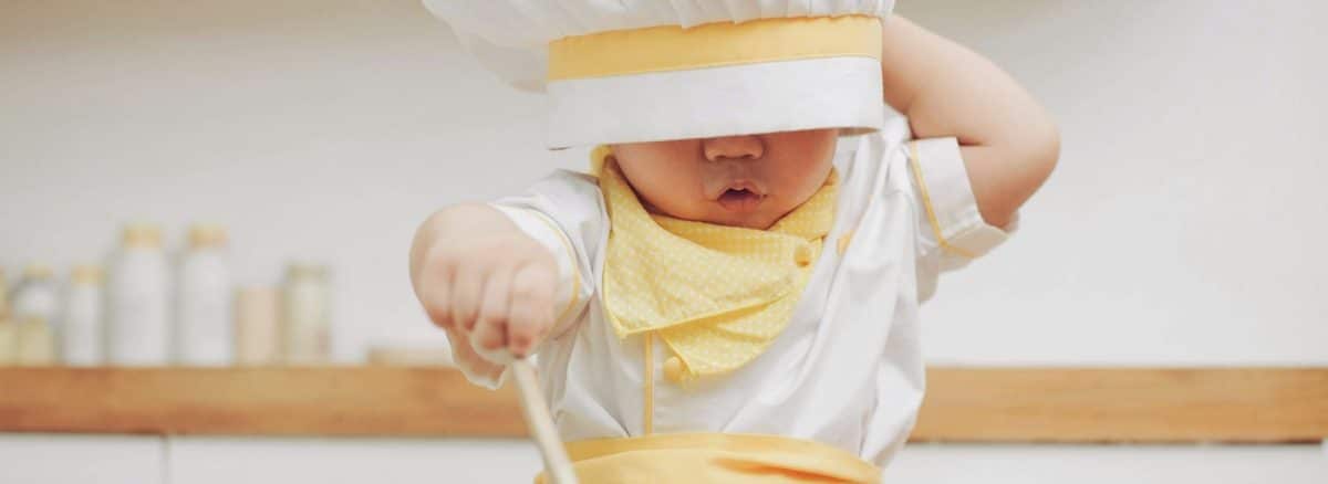 a young child wearing a chef's hat and holding a spoon