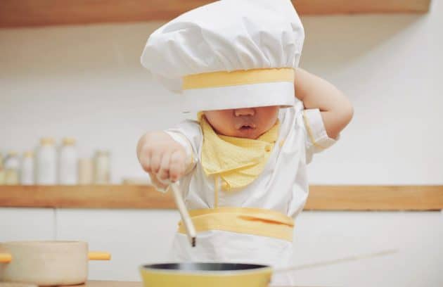 a young child wearing a chef's hat and holding a spoon