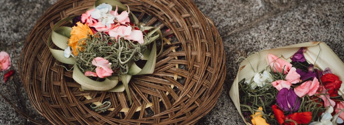 two baskets of flowers on the ground next to each other