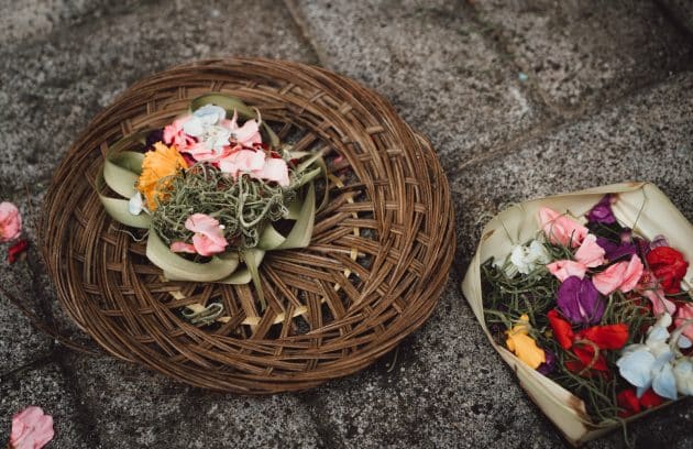 two baskets of flowers on the ground next to each other