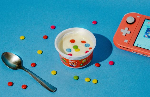 a cup of yogurt and a spoon on a blue surface