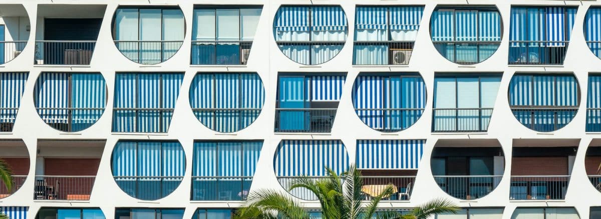 a tall building with many windows and palm trees in front of it