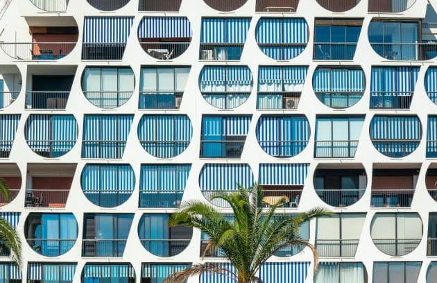 a tall building with many windows and palm trees in front of it