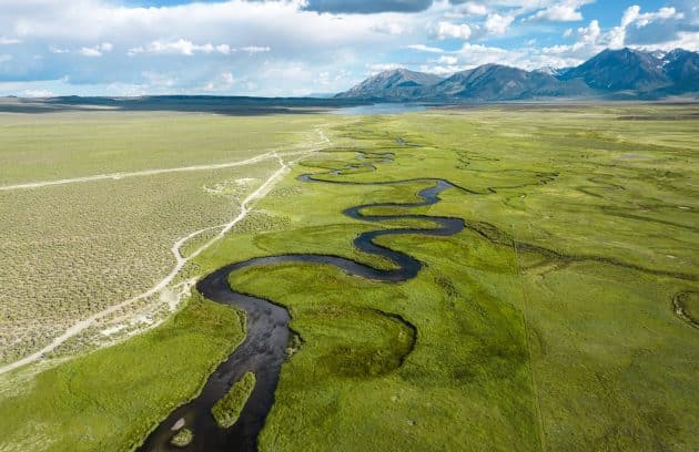 a wide open field with a river running through it