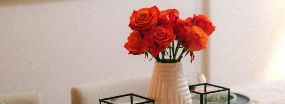 a table with a vase of red roses on it