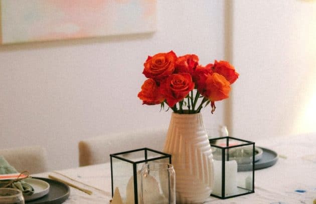 a table with a vase of red roses on it