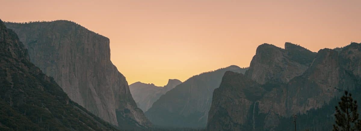 the sun is setting over the mountains in the valley