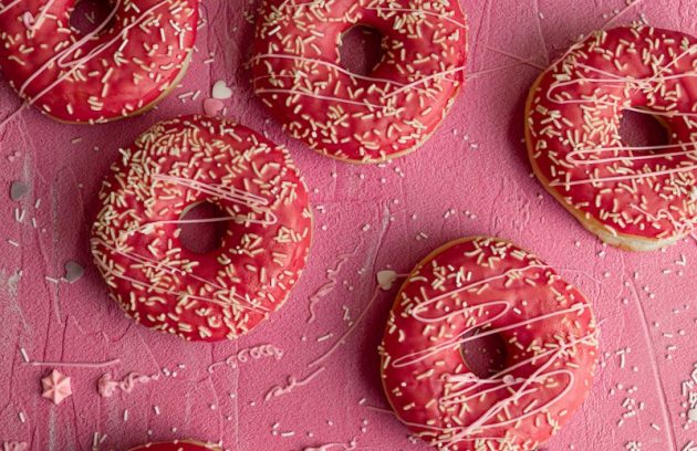 a bunch of doughnuts that are on a pink surface