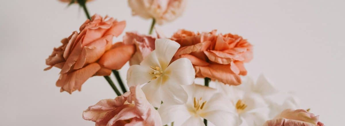 a white vase filled with pink and white flowers