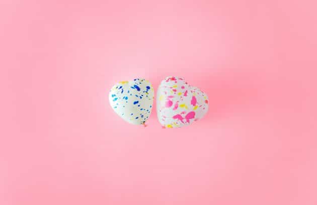 two heart-shaped balloons on a pink background