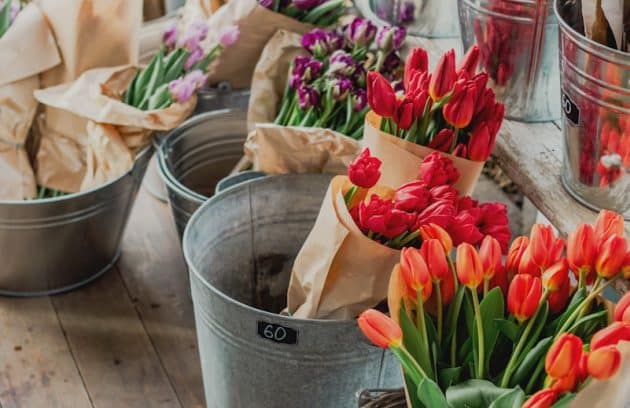 a wooden table topped with buckets filled with flowers